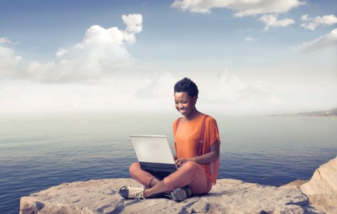 Girl sitting outdoors working on laptop