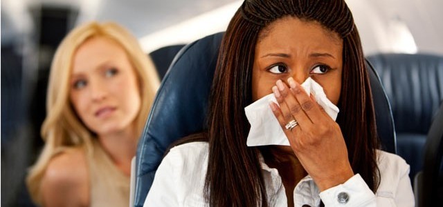 A passenger holds a cloth over her nose and mouth as the airplane cabin spraying commences.