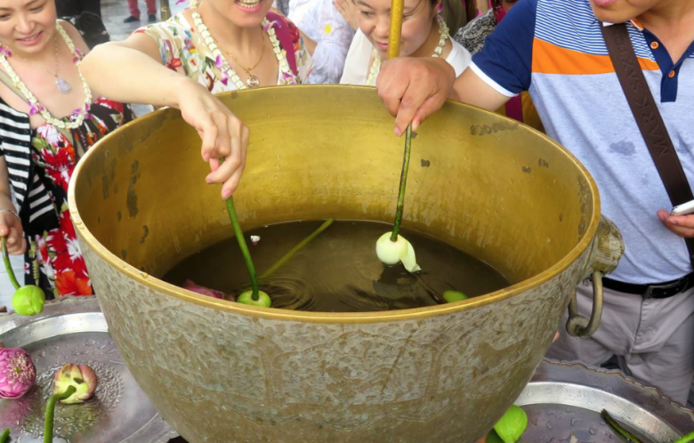 At the Grand Palace, dipping lotus flowers in water for a blessing.