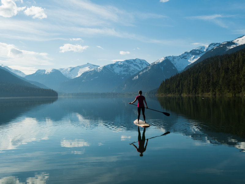 Woman stand up paddle boarding on a pristine mountain lake best time to visit Canada