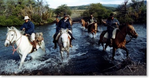 Riders on horseback crossing a river in argentina