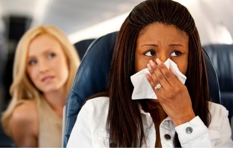 A passenger holds a cloth over her nose and mouth as the airplane cabin spraying commences.