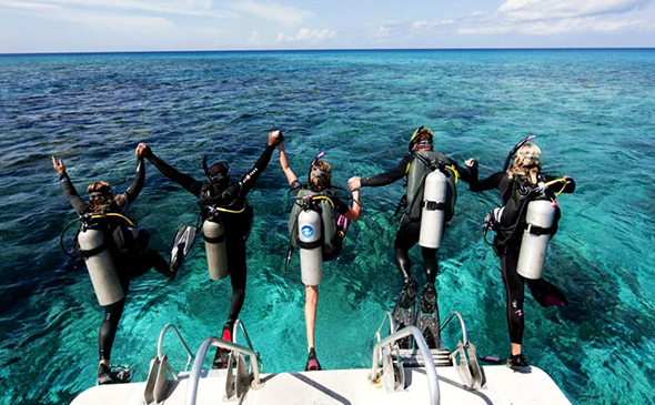Travellers holding hands while jumping into the water to do some scuba diving in Thailand