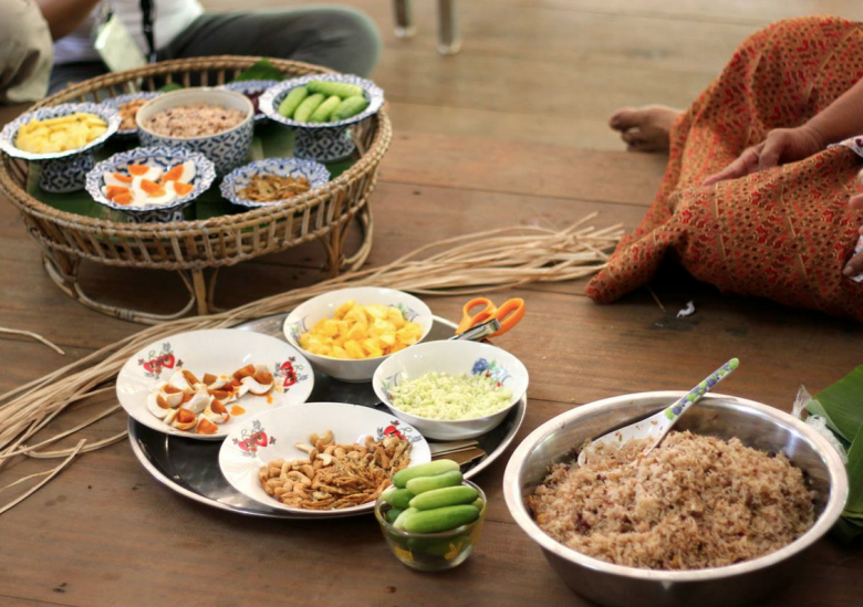 Making betel palm leaf wraps, a traditional lunch pack with rice, salty eggs, walnuts, onion, pineapple.