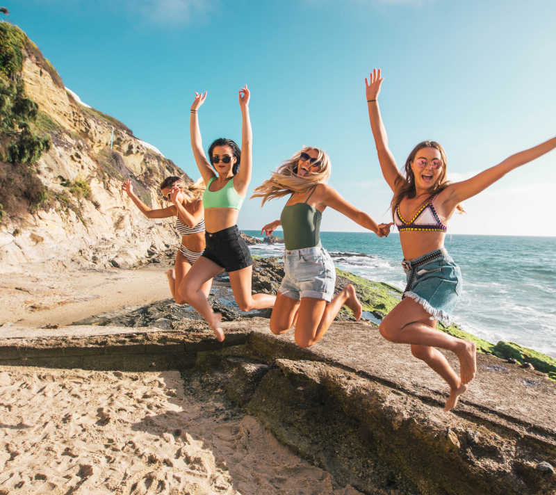 Four women jumping on the coast