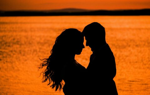 Couple embracing in the ocean during a sunset. Here are the top 7 romantic Valentine's getaway in South Africa 2025.