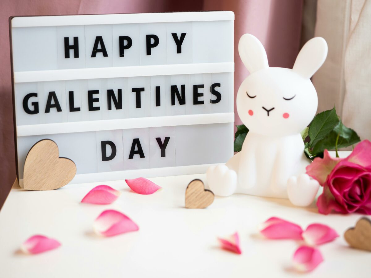 A lightbox sign with 'Happy Galentine's Day' in bold black letters, surrounded by pink rose petals, wooden hearts, and a cute white bunny figurine. This is a blog about the top 7 Galentine's Day Getaways in South Africa in 2025