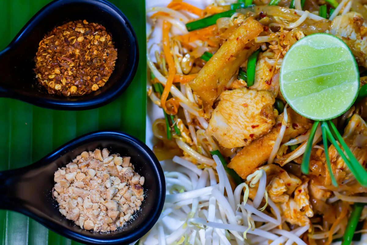 A vibrant Thai street food spread featuring grilled skewers, fried snacks, and dipping sauces on a market table. Bangkok is well known for street food.