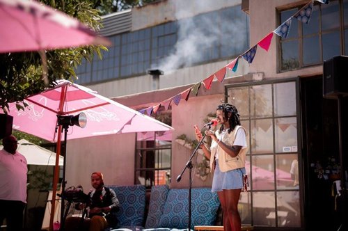 Woman singing with a live band at the Victoria Yards. This is a free music concert in Johannesburg.