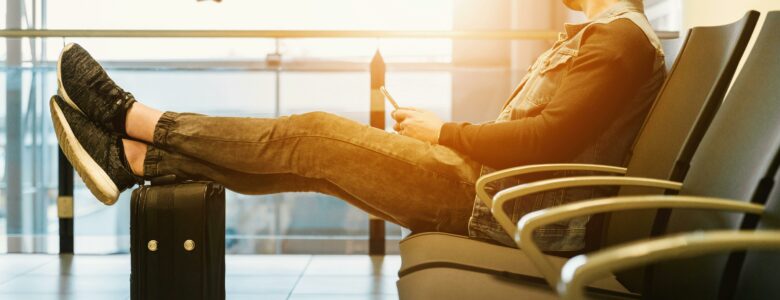 Man sitting in an airport looking out to an airplane taking off.