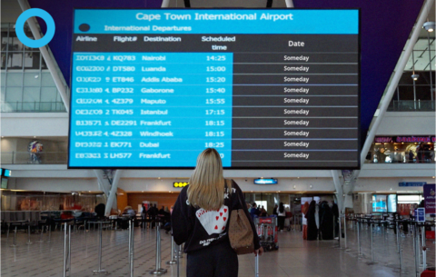 Lady looking at the flight boards at the airport wondering why flights are so expensive