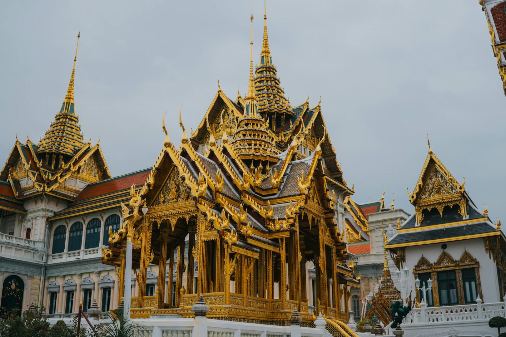 The Grand Palace in Bangkok with golden spires and intricate Thai architecture under a clear blue sky.