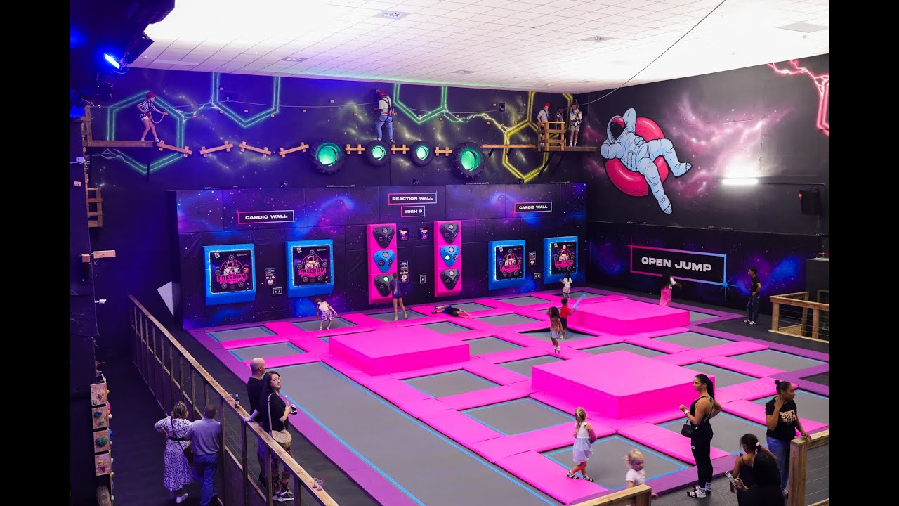 Kids and adults bounce on bright pink trampolines under neon lights at Freedom Adventure Park in Cape Town, the perfect indoor escape during winter.