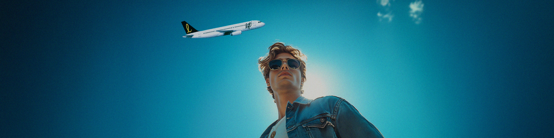 An upward angle of a man having a LIFT airline plane flying overhead in the blue sky