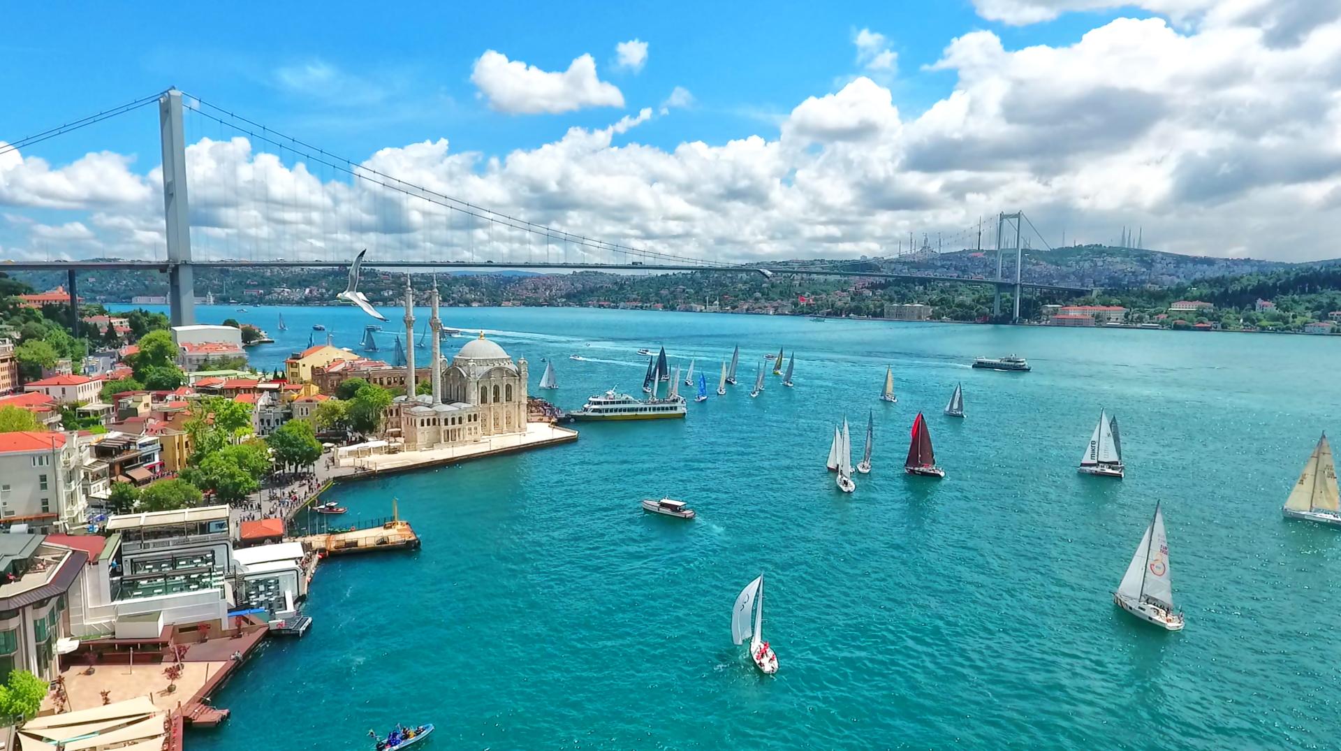 Scenic view of the Bosphorus Strait in Istanbul, Turkey, featuring sailboats, the Ortaköy Mosque, and the Bosphorus Bridge under a bright blue sky. Top 5 cheap Rand-frienldy travel deals for Black Friday 2025