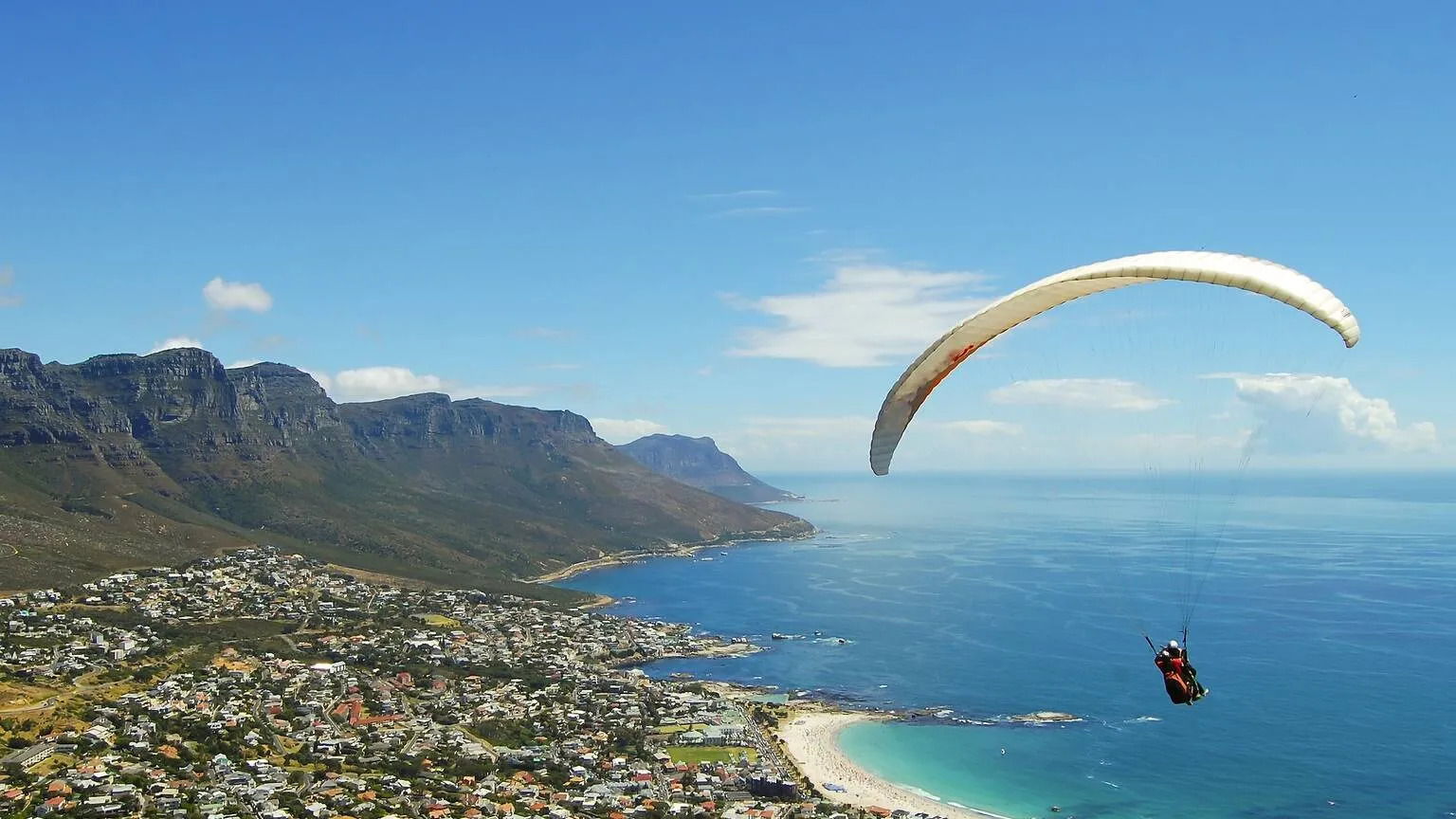 People paragliding over an aerial view Cape Town showing the mountains, the city architecture and the blue sea. The multiple activities in Cape Town have helped in ranking it as Timeout's best city in the World 2025.
