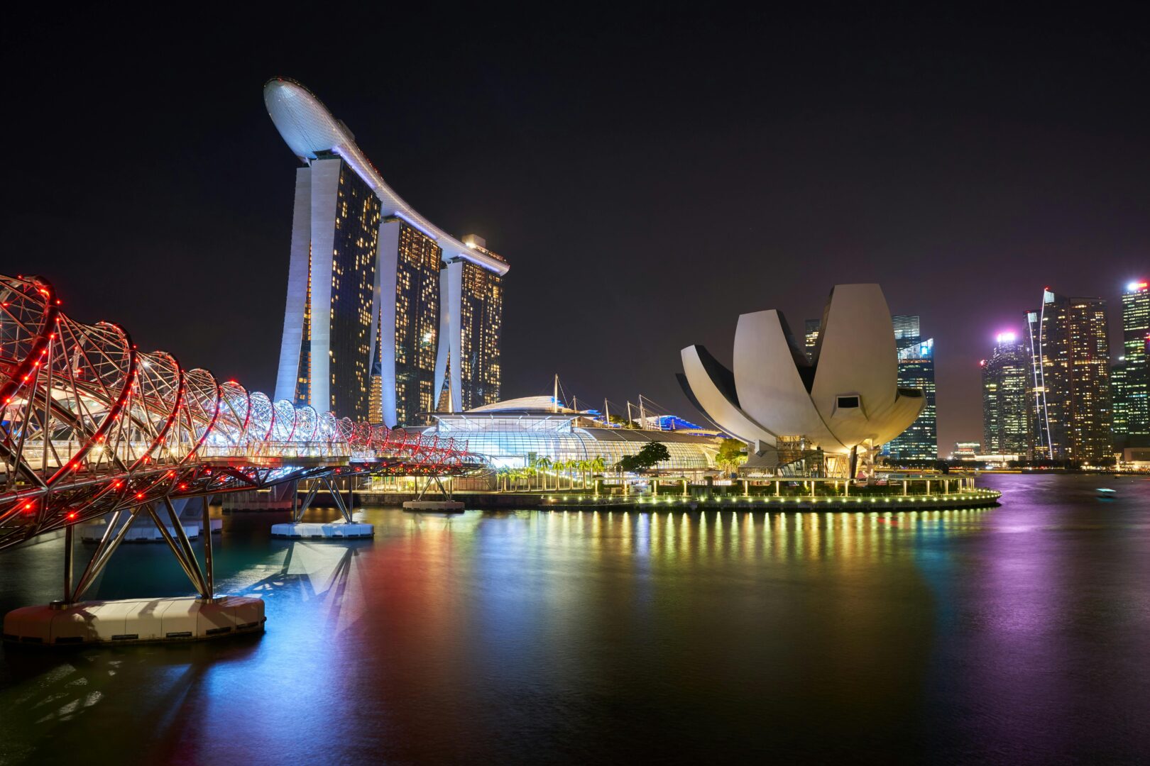 A night time view of Singapore, skyscrapers and calm ocean water. Singapore is one of the top holiday destinations for South Africans to visit.