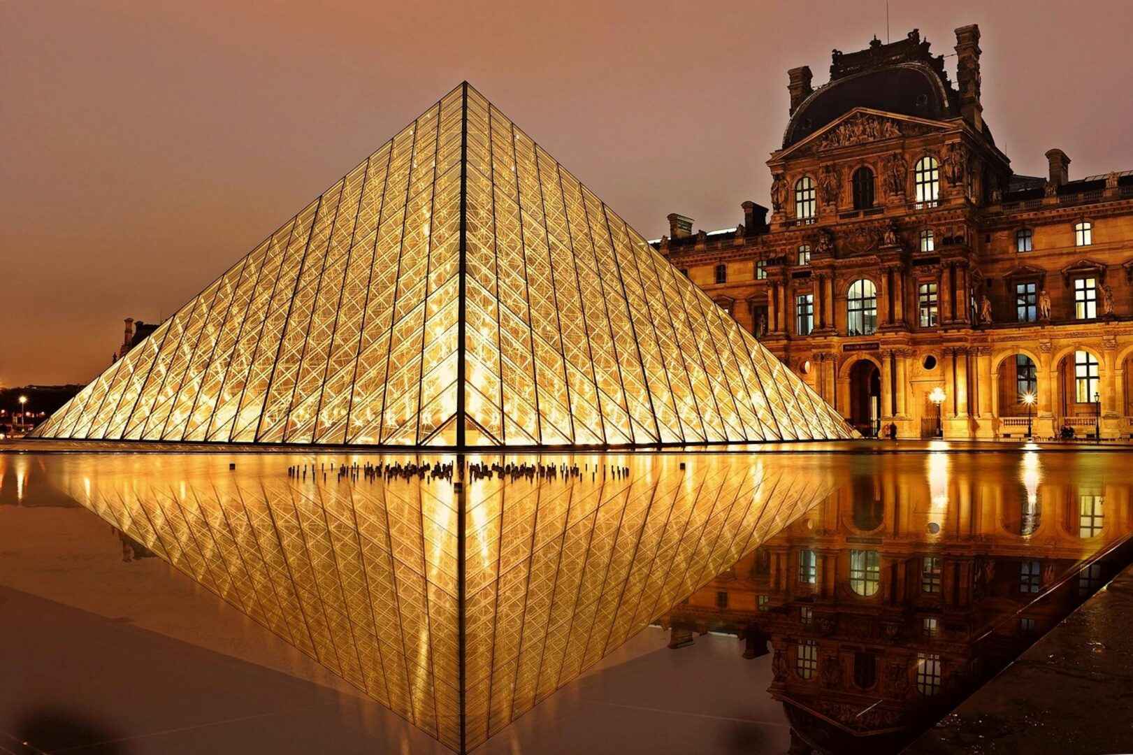 The louvre in Paris, brightly lit in golden light at night. This is one of the the top travel bucket list places for South Africans to visit in 2025