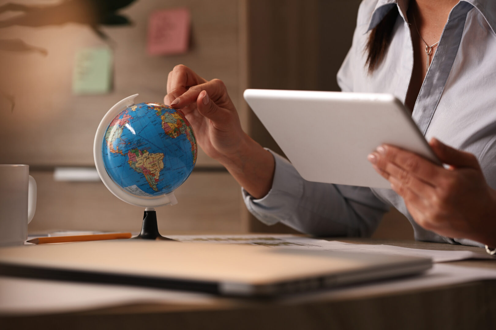 businesswoman using digital tablet while examining globe and planning her vacation.  Concept image for how South Africans can land overseas jobs